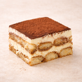 Layered tiramisu dessert with chocolate crumb topping on a beige background